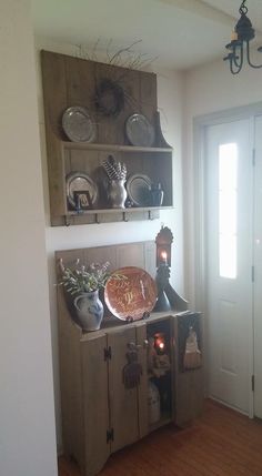 a wooden shelf filled with dishes on top of a hard wood floor next to a door