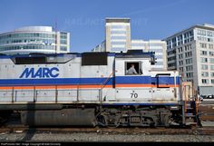 an old train is parked on the tracks in front of some buildings and skyscrapers