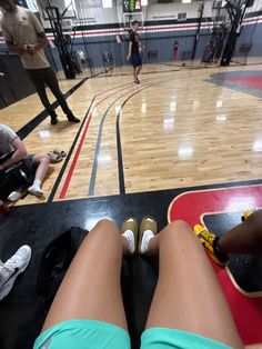 people are sitting on the floor in a gym with their feet up and one person standing