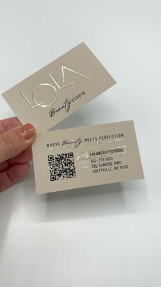 a person is holding two business cards in their left hand and the other one has a qr code on it