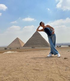 a woman standing in front of three pyramids with her hands on her head and looking at the camera