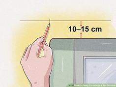 a hand holding a pencil near a drawing board with measurements for the area in front of it