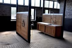 two sinks in a room with brick walls and large windows on either side of them