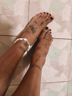 two people with tattoos on their legs standing in front of a tiled wall and floor