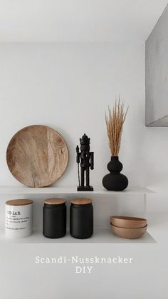 a shelf with vases and other items on top of it in a white room