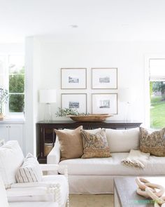 a living room filled with white furniture and lots of pillows on top of it's couches