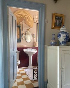 an open door leading to a bathroom with a checkered floor and white pedestal sink