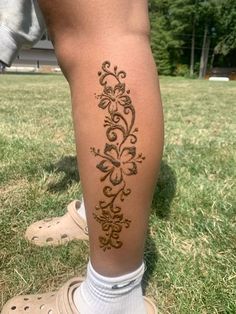 a person standing in the grass with their legs crossed and tattooing on her leg