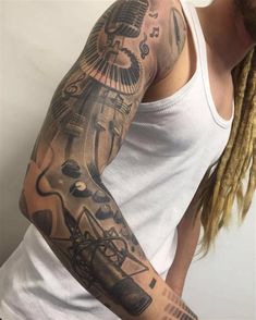 a man with dreadlocks and a white tank top has a tattoo on his arm