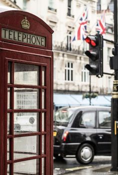 a red telephone booth sitting on the side of a road next to a traffic light