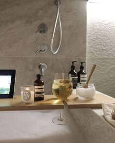 a bath room with a tub a monitor and some glasses on the counter next to it