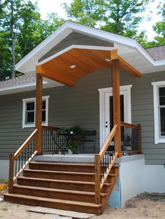 a small gray house with stairs leading to the front door and covered porch area on one side