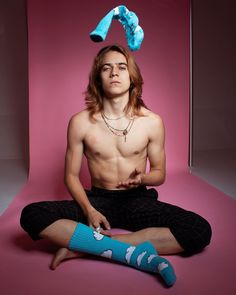 a shirtless man sitting on the floor with his legs crossed and wearing blue socks