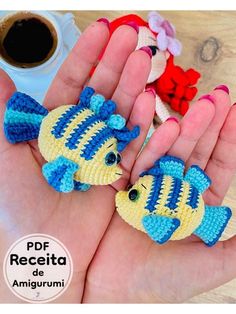 two small crocheted toy fish sitting in the palm of someone's hand