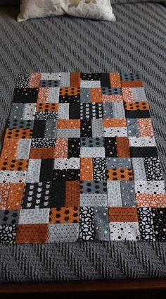 an orange and black quilt on a bed