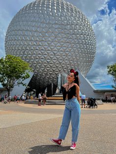 a woman standing in front of a large ball at the epcoti disney world