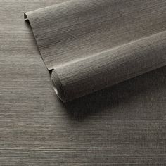 a roll of gray fabric on top of a wooden flooring board with grey stripes