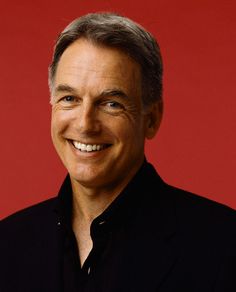 a close up of a person wearing a black shirt and smiling with a red background