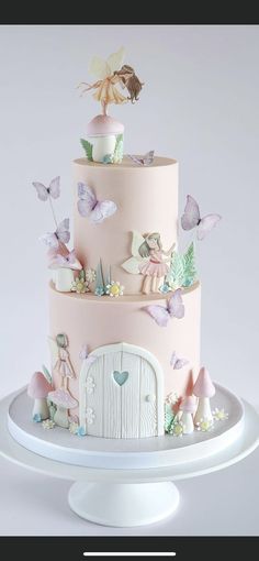 a three tiered cake with fairy figurines on top and pink frosting