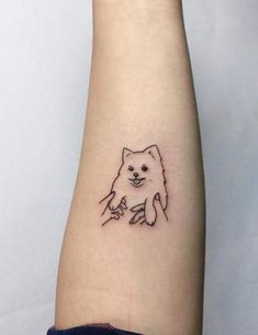 a small dog tattoo on the left forearm and arm, with a hand holding a paw