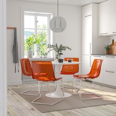 an image of a dining room setting with orange chairs and round table in the middle