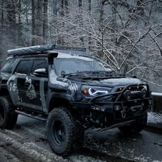 a black truck driving down a snow covered road