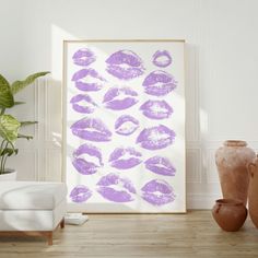 a white frame with purple lipstick prints on it next to vases and potted plant