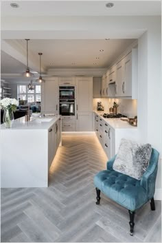 a blue chair sitting in the middle of a kitchen next to a counter top oven