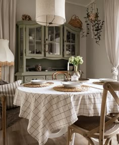 a dining room with a table and chairs in front of a hutch filled with dishes