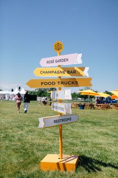 there are many signs in the grass pointing to different locations and places for food trucks