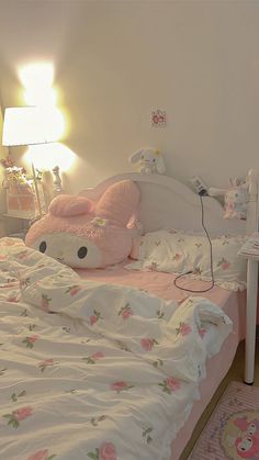 there is a bed with pink sheets and pillows on it, next to a lamp