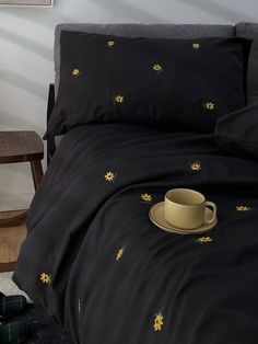 a cup and saucer sitting on top of a bed next to a wooden table