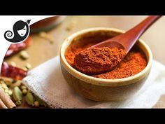 a wooden spoon filled with red powder next to spices