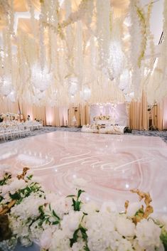 an elaborately decorated ballroom with chandeliers and white flowers on the dance floor