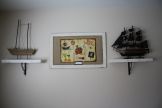 there are three shelves on the wall that have boats and other items on them,