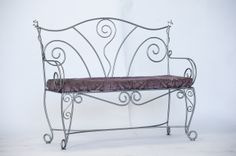 a wrought iron bench with a purple velvet seat cover on it's backrest