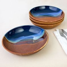 two blue and brown plates with silverware next to each other on a white table