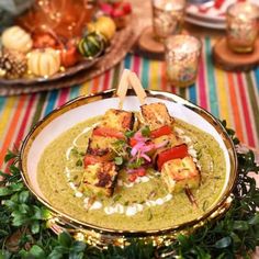 a plate filled with tofu skewers and garnishes on top of green sauce