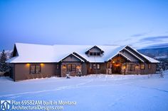 a large house in the middle of a snow covered field with lights on it's windows