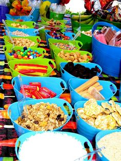 several buckets filled with different types of food on a table covered in candy bars