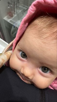 a baby wearing a pink hoodie and holding a banana