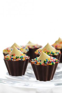 chocolate cupcakes with white frosting and sprinkles on a glass plate