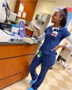 a woman in scrubs standing next to a counter