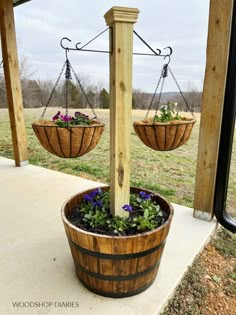 two wooden buckets with flowers in them hanging from a porch rail and on the side of a building