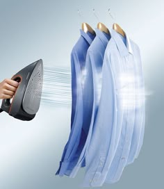 a woman is drying clothes on a line with an iron and dryer in front of her