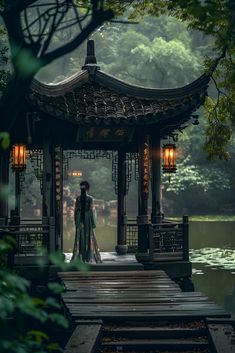 a woman is standing in front of a gazebo by the water with lanterns on it