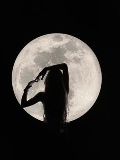 a woman standing in front of a full moon with her hands on her hips and arms outstretched