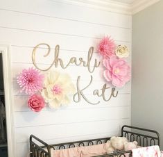 a baby's crib with pink and white flowers on the wall above it