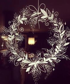 a white christmas wreath hanging from the side of a door with stars and swirls on it