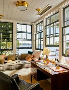 a living room filled with furniture and lots of windows next to a large body of water